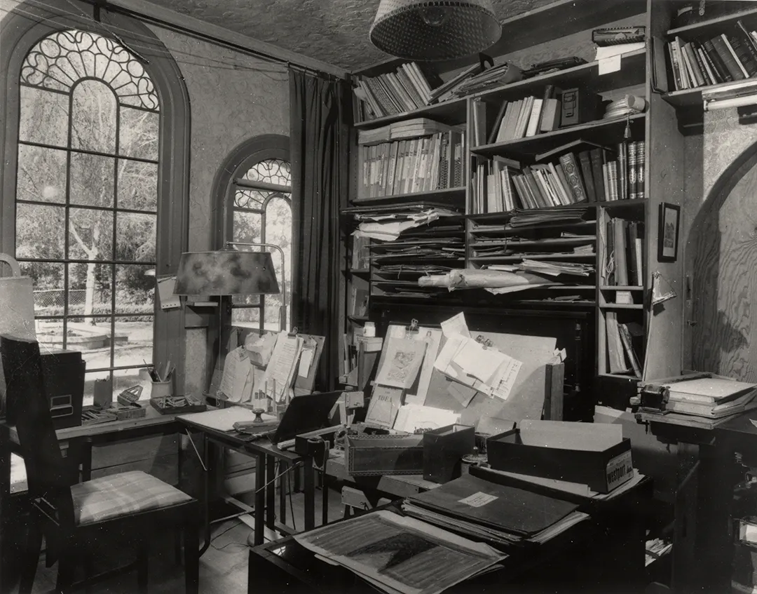 Arnold Schoenberg's study, with office furniture, bookshelves with many books and papers, and two arched windows